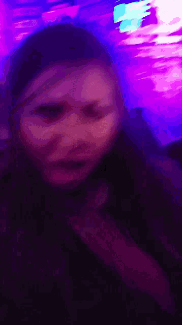 a blurry picture of a woman 's face with purple lights behind her