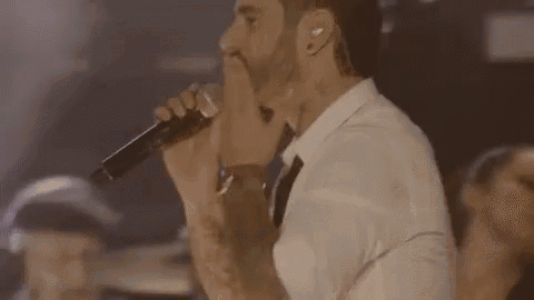 a man in a white shirt is singing into a microphone .