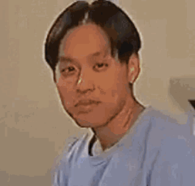 a man in a blue shirt is looking at the camera .
