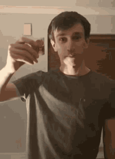a young man is holding a strawberry in his hand in front of his face .