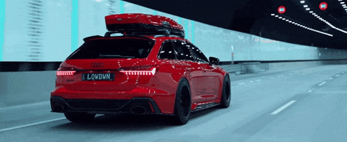 a red audi is driving through a tunnel with a roof box on top of it