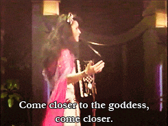 a woman singing in front of a microphone with the words come closer to the goddess come closer