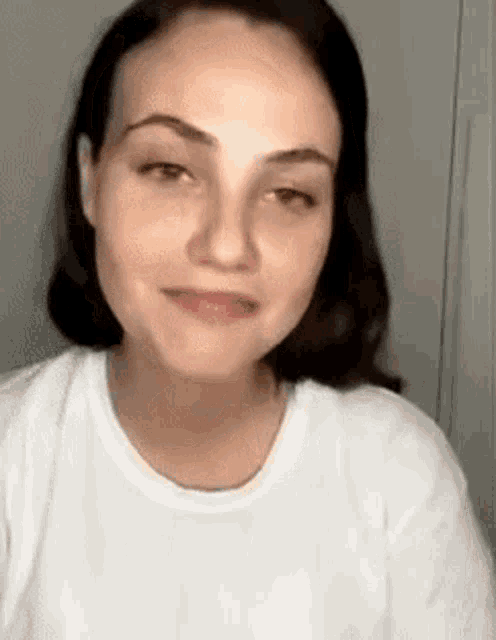 a close up of a woman 's face wearing a white t-shirt .