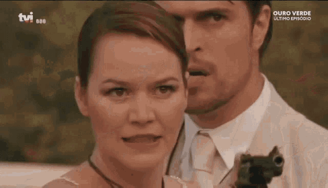 a man and a woman are standing next to each other and the man is holding a gun in his hand .