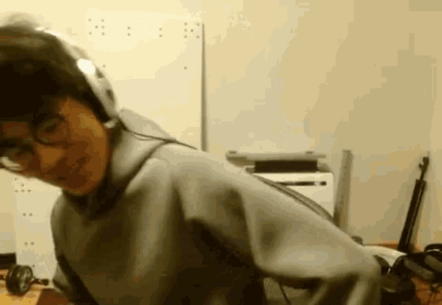 a man wearing headphones and glasses is standing in front of a computer .