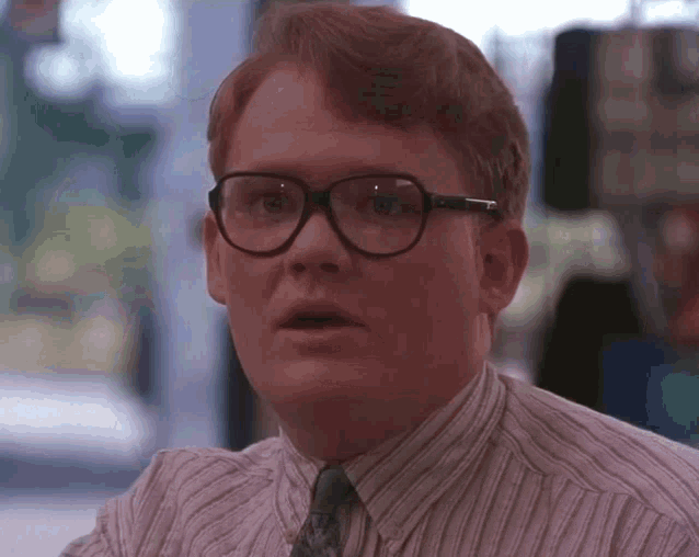 a man wearing glasses and a striped shirt is looking at the camera