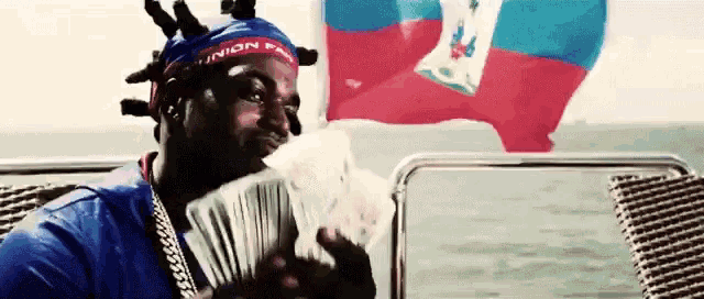 a man on a boat holding a bunch of money with a union flag in the background