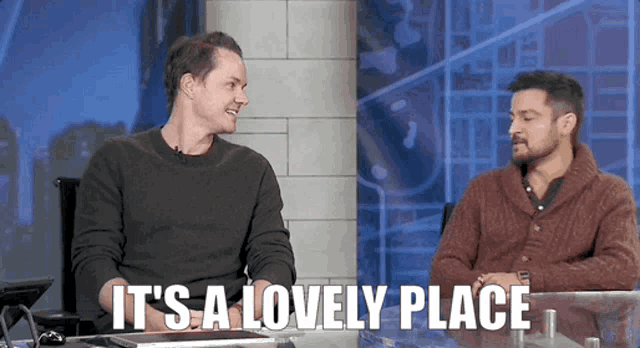 two men sitting at a table with the words " it 's a lovely place "
