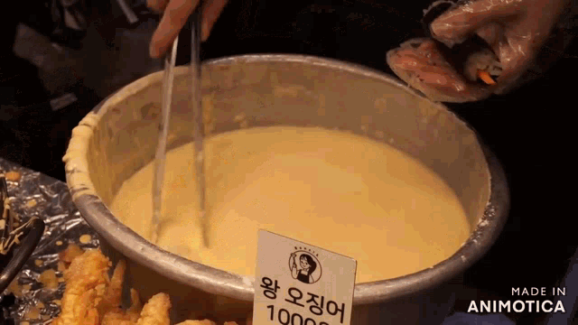 a bowl of sauce with tongs and a sign that says made in animotica