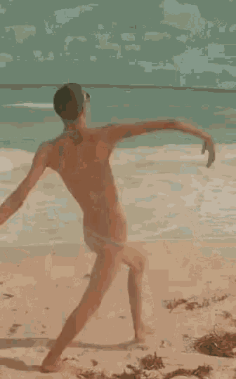 a shirtless man in a bikini is standing on a beach