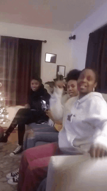 a group of people are sitting on a couch and one of them is wearing a sweatshirt with the letter t on it