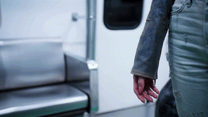 a person 's hand is visible in a blurry photo while standing in a subway car .