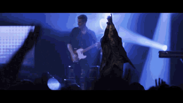a man playing a guitar and a man singing on stage