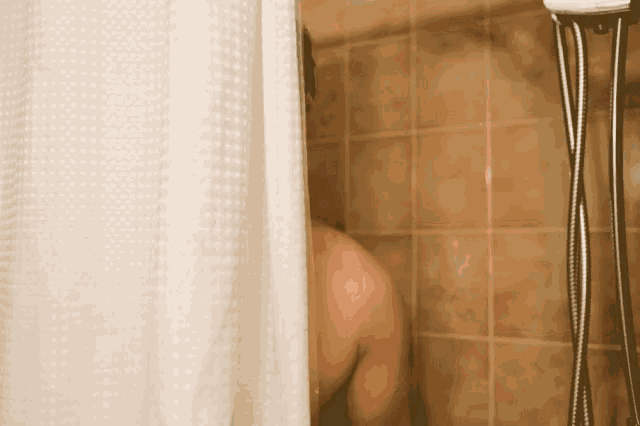 a man taking a shower with a white shower curtain behind him
