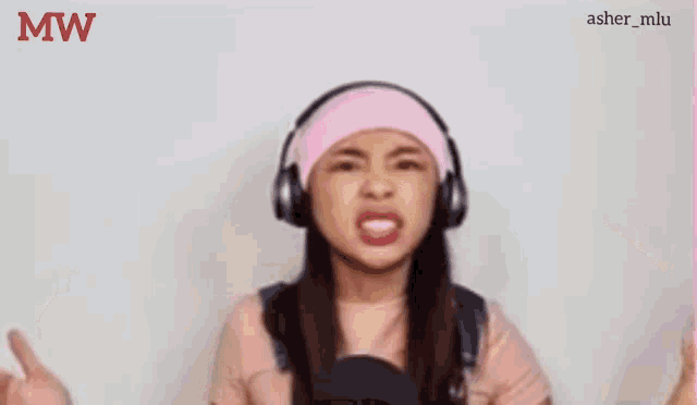 a girl wearing headphones and a pink headband is making a funny face