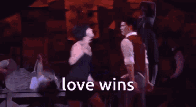 a man and a woman are dancing on a stage and the words love wins are visible .