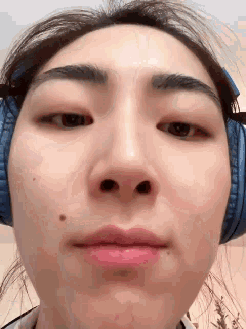 a close up of a woman wearing headphones making a face
