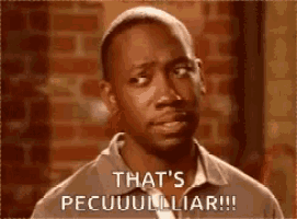a man is standing in front of a brick wall and saying `` that 's pecuuulliar ! ''