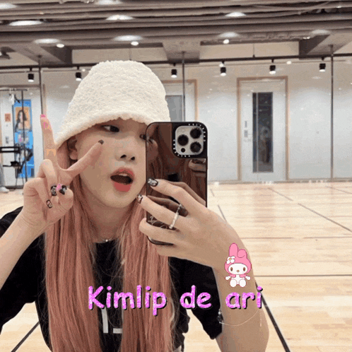 a girl taking a picture of herself in a mirror with kimlip de ari written above her
