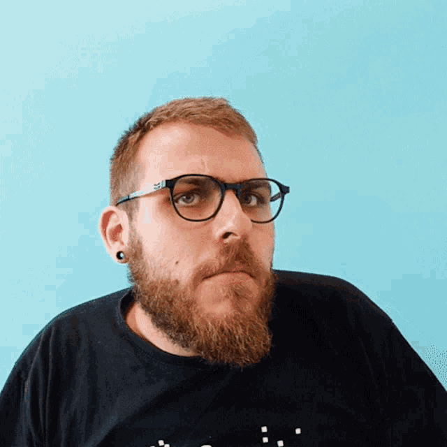 a man with glasses and a beard is wearing a black shirt with the letter s on it