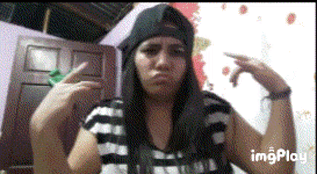 a girl wearing a black hat and a striped shirt is making a funny face ..