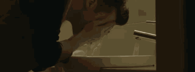 a man is washing his face in a sink