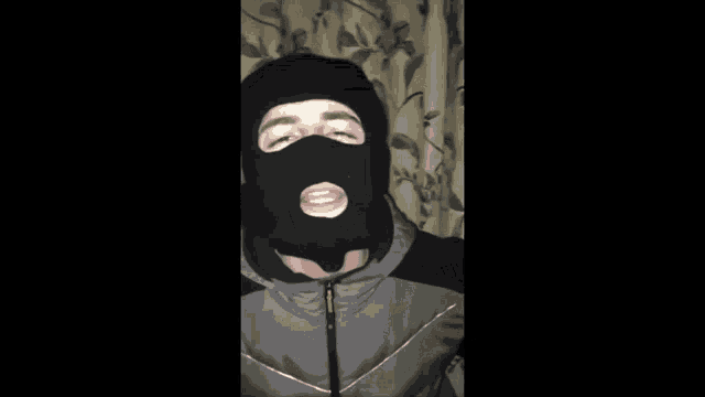 a man wearing a black ski mask is giving a thumbs up