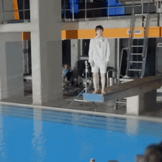 a man is standing on a diving board in front of a pool