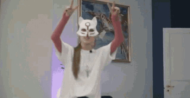 a woman wearing a cat mask and a white shirt is dancing in a room .