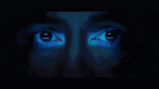 a close up of a person 's face with a blue light coming out of their eyes .