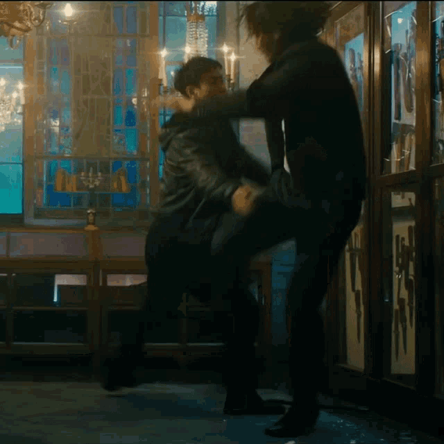 a man kicking another man in the face in front of a display of knives