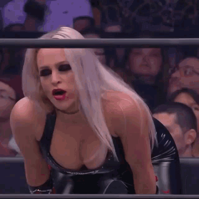 a woman in a black latex dress is standing in a ring