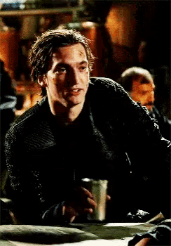 a man is sitting at a table holding a can of beer