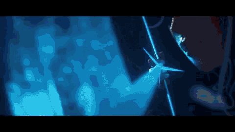 a person is holding a sword in a dark room with a blue light shining on them .
