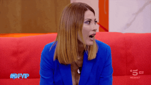 a woman in a blue jacket is sitting on a red couch with the words #gfvip on the bottom
