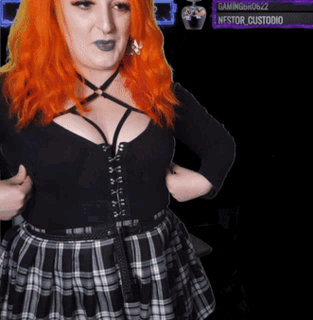 a woman with red hair is wearing a plaid skirt and a black shirt