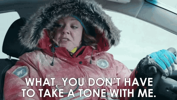 a woman in a red jacket is driving a car and saying " what you don 't have to take a tone with me "