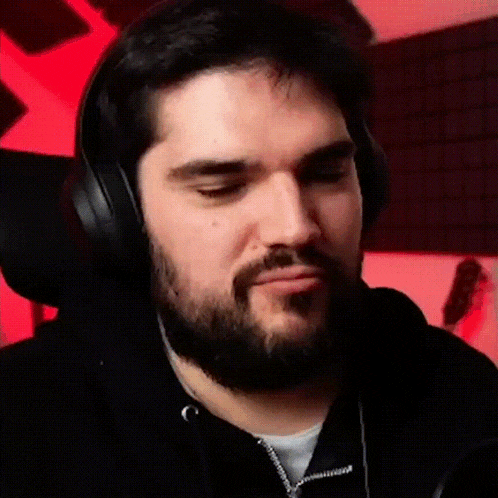 a man with a beard wearing headphones making a funny face .