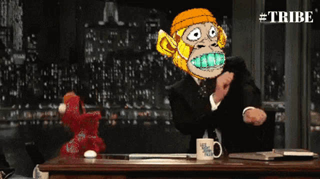 a man in a suit is sitting at a desk with elmo and a mug that says late night with sesame street
