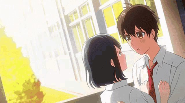 a boy and a girl are kissing in front of a window in a hallway .