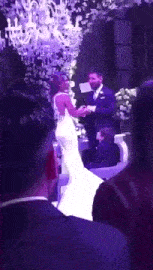 a bride and groom are holding hands during their wedding ceremony in front of a crowd of people .