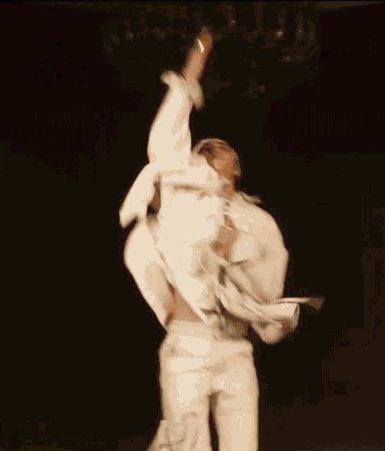 a blurry picture of a man in a white suit dancing in the dark .