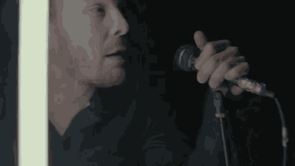 a man in a black shirt is singing into a microphone .