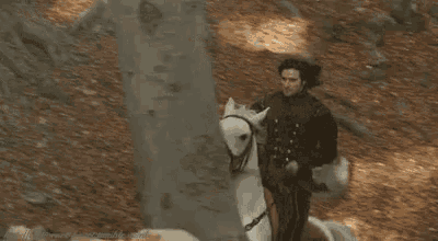 a man is riding a white horse through a cave .
