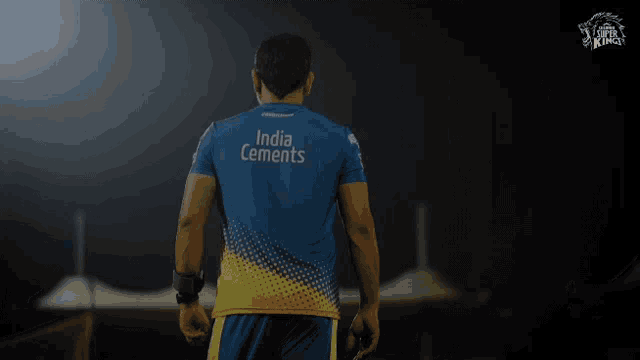 a man is wearing a blue and yellow india cements shirt