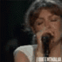 a close up of a woman singing into a microphone
