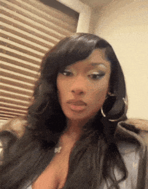 a woman wearing a plunging neckline and hoop earrings is looking at the camera .