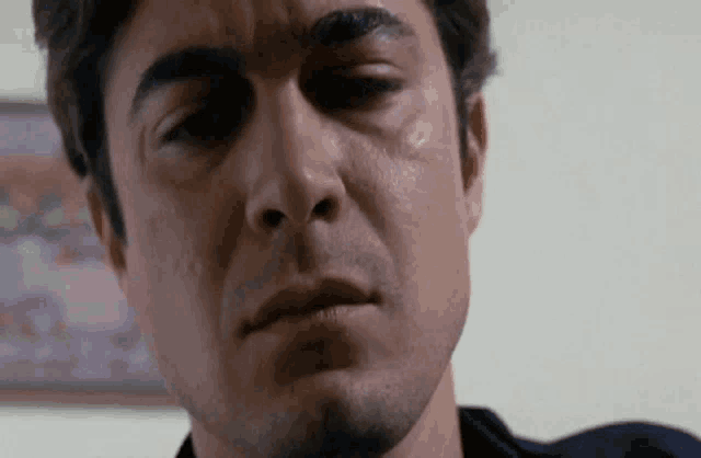 a close up of a man 's face with a tear running down his eye .