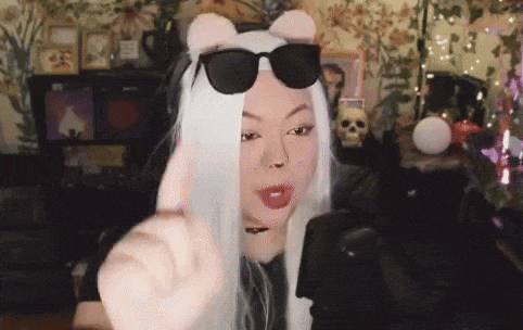 a woman wearing a wig and sunglasses is giving a thumbs up sign .