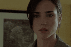 a close up of a woman 's face in front of a yellow wall